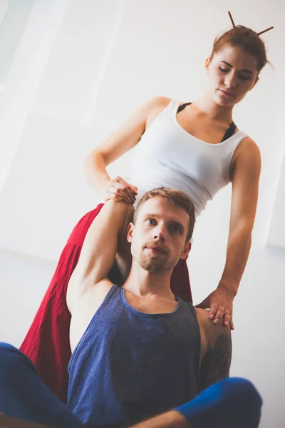 Young healthy couple in yoga position on white background