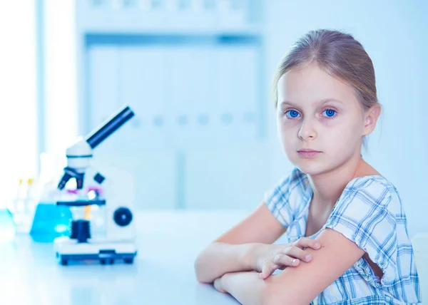 Colegiala mirando a través del microscopio en la clase de ciencias . — Foto de Stock