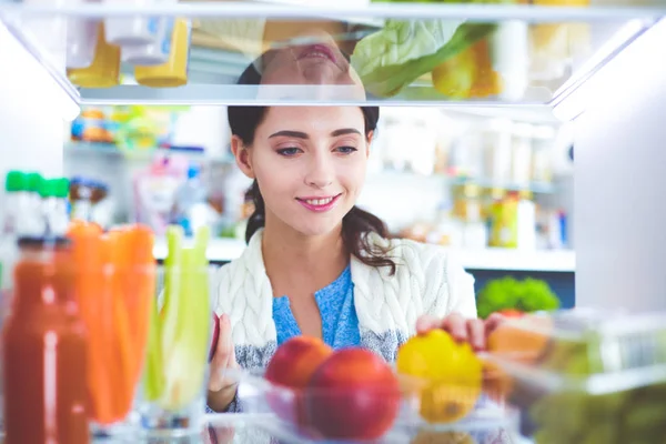 Retrato de fêmea em pé perto da geladeira aberta cheia de alimentos saudáveis, legumes e frutas. Retrato de fêmea — Fotografia de Stock