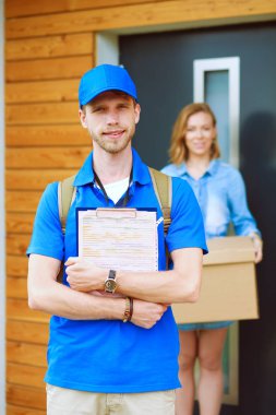 Mavi üniformalı gülümseyen kurye servis konseptine paket kutusu teslim eden teslimatçı. Mavi üniformalı gülümseyen teslimatçı.
