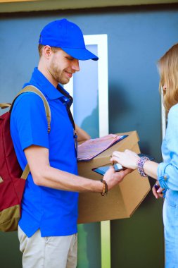 Mavi üniformalı gülümseyen kurye servis konseptine paket kutusu teslim eden teslimatçı. Mavi üniformalı gülümseyen teslimatçı.
