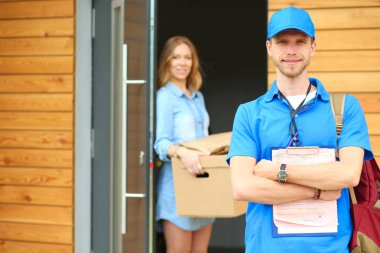 Mavi üniformalı gülümseyen kurye servis konseptine paket kutusu teslim eden teslimatçı. Mavi üniformalı gülümseyen teslimatçı.