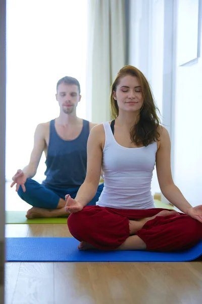 Joven pareja sana en posición de yoga sobre fondo blanco —  Fotos de Stock