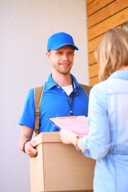 Mavi üniformalı gülümseyen kurye servis konseptine paket kutusu teslim eden teslimatçı. Mavi üniformalı gülümseyen teslimatçı.
