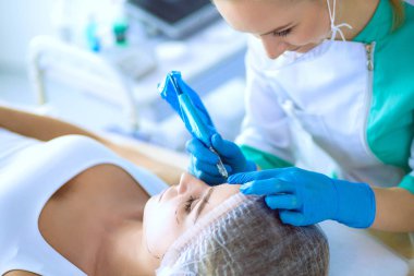 Kaşlar için kalıcı makyaj. Güzellik salonunda kalın kaşlı güzel bir kadın.