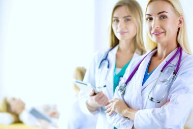 Tıp ofisinde kollarını kavuşturmuş kendine güvenen kadın doktorların portresi.