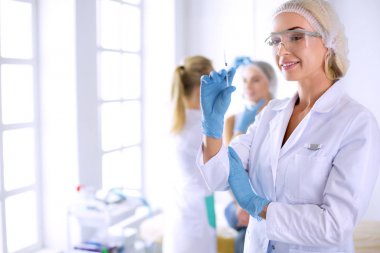 Güzel kadın elinde şırıngayla doktorun yanında duruyor.