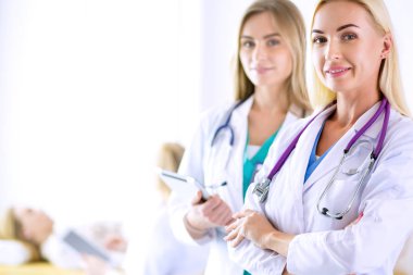 Tıp ofisinde kollarını kavuşturmuş kendine güvenen kadın doktorların portresi.