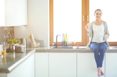 Mutfakta dijital tablet kullanan güzel genç bir kadın..