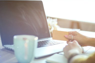 Kredi kartı tutan ve dizüstü bilgisayar kullanan genç bir kadın. Çevrimiçi alışveriş kavramı