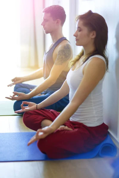 Joven pareja sana en posición de yoga sobre fondo blanco — Foto de Stock