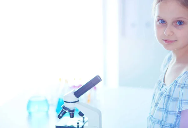 Colegiala mirando a través del microscopio en la clase de ciencias . — Foto de Stock