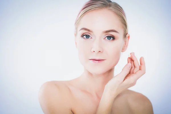 Portret van een vrolijke glimlachende mooie jonge vrouw die de huid aanraakt of crème aanbrengt, geïsoleerd over een witte achtergrond — Stockfoto