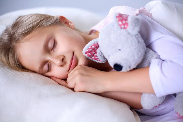 Kind meisje slaapt in het bed met een speeltje teddy beer — Stockfoto