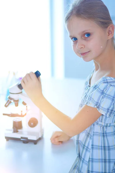 Schoolmeisje op zoek via Microscoop in de wetenschap klasse. — Stockfoto