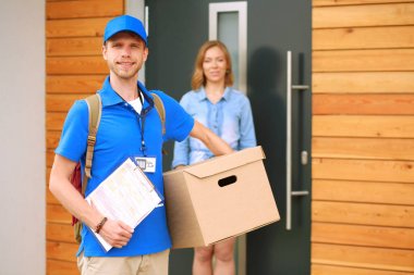Mavi üniformalı gülümseyen kurye servis konseptine paket kutusu teslim eden teslimatçı. Mavi üniformalı gülümseyen teslimatçı.