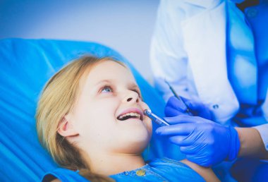 Küçük kız dişçi ofisinde oturuyor..