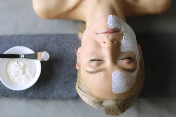 Mascarilla facial. Hermosa joven en el spa, mujer cosmética aplicando mascarilla facial . — Foto de Stock