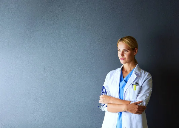 Portret van een jonge vrouwelijke arts met witte jas in het ziekenhuis. — Stockfoto