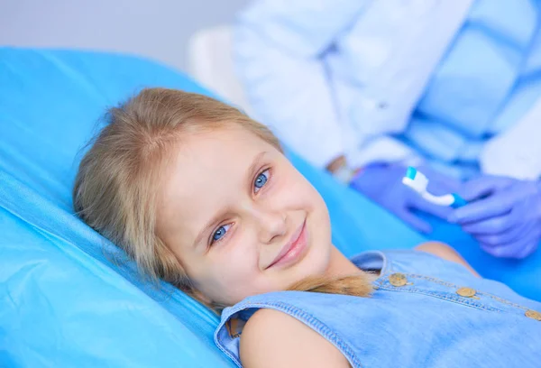 Klein meisje zit in het tandartspraktijk. — Stockfoto