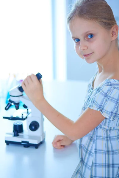 Colegiala mirando a través del microscopio en la clase de ciencias . — Foto de Stock