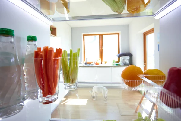 Retrato de una mujer parada cerca de una nevera abierta llena de alimentos saludables, verduras y frutas. Retrato de mujer — Foto de Stock