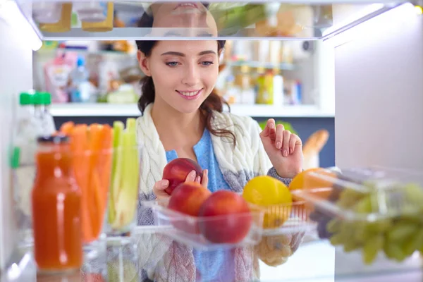 Retrato de fêmea em pé perto da geladeira aberta cheia de alimentos saudáveis, legumes e frutas. Retrato de fêmea — Fotografia de Stock