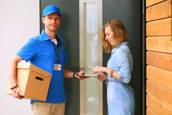 Repartidor sonriente con uniforme azul que entrega la caja de paquetes al destinatario: concepto de servicio de mensajería. Repartidor sonriente en uniforme azul — Foto de Stock