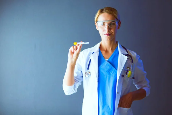 Medizinische oder wissenschaftliche Wissenschaftlerin oder Ärztin mit Blick auf ein Reagenzglas mit klarer Lösung in einem Labor oder Labor. — Stockfoto