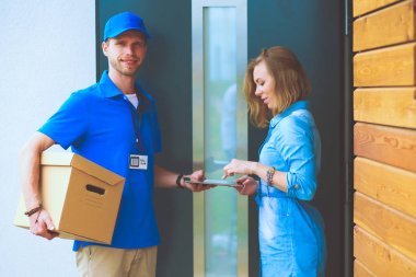Mavi üniformalı gülümseyen kurye servis konseptine paket kutusu teslim eden teslimatçı. Mavi üniformalı gülümseyen teslimatçı.
