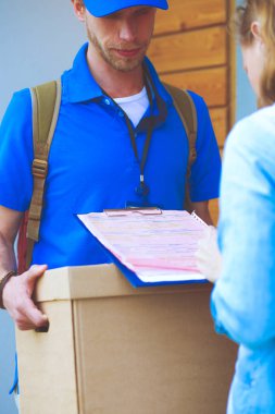 Mavi üniformalı gülümseyen kurye servis konseptine paket kutusu teslim eden teslimatçı. Mavi üniformalı gülümseyen teslimatçı.