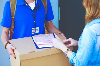 Mavi üniformalı gülümseyen kurye servis konseptine paket kutusu teslim eden teslimatçı. Mavi üniformalı gülümseyen teslimatçı.