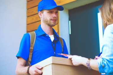 Mavi üniformalı gülümseyen kurye servis konseptine paket kutusu teslim eden teslimatçı. Mavi üniformalı gülümseyen teslimatçı.