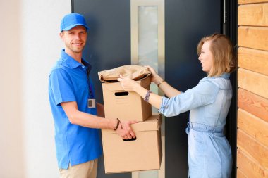 Mavi üniformalı gülümseyen kurye servis konseptine paket kutusu teslim eden teslimatçı. Mavi üniformalı gülümseyen teslimatçı.