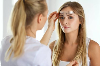 Kaşlar için kalıcı makyaj. Güzellik salonunda kalın kaşlı güzel bir kadın..