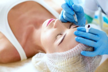 Kaşlar için kalıcı makyaj. Güzellik salonunda kalın kaşlı güzel bir kadın..