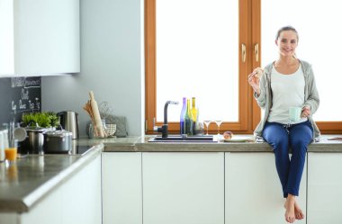 Mutfakta dijital tablet kullanan güzel genç bir kadın..