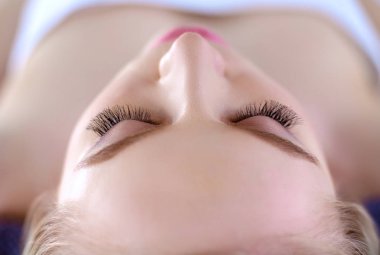 Masaj masasında uzanmış gözleri kapalı rahatlayan genç bir kadın. - Kadın. Spa salonu