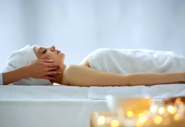 Masaj masasında uzanmış gözleri kapalı rahatlayan genç bir kadın. - Kadın. Spa salonu