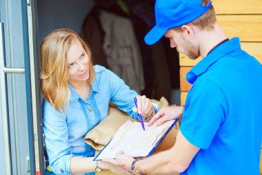 Mavi üniformalı gülümseyen kurye servis konseptine paket kutusu teslim eden teslimatçı. Mavi üniformalı gülümseyen teslimatçı.