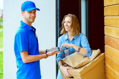 Mavi üniformalı gülümseyen kurye servis konseptine paket kutusu teslim eden teslimatçı. Mavi üniformalı gülümseyen teslimatçı.