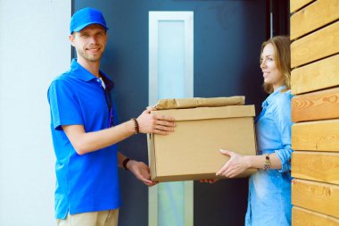 Mavi üniformalı gülümseyen kurye servis konseptine paket kutusu teslim eden teslimatçı. Mavi üniformalı gülümseyen teslimatçı.