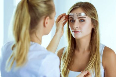 Kaşlar için kalıcı makyaj. Güzellik salonunda kalın kaşlı güzel bir kadın..