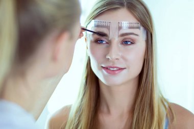 Kaşlar için kalıcı makyaj. Güzellik salonunda kalın kaşlı güzel bir kadın..