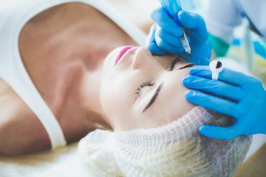 Kaşlar için kalıcı makyaj. Güzellik salonunda kalın kaşlı güzel bir kadın..