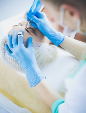 Kaşlar için kalıcı makyaj. Güzellik salonunda kalın kaşlı güzel bir kadın..