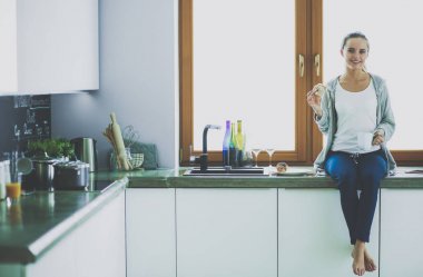 Mutfakta dijital tablet kullanan güzel genç bir kadın..