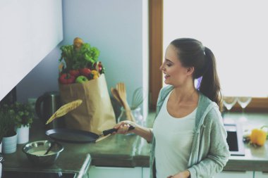 Genç bayan masanın yanında dururken mutfakta krep hazırlıyor. Mutfaktaki kadın. Mutfakta yemek yapmak..