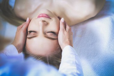 Masaj masasında uzanmış gözleri kapalı rahatlayan genç bir kadın. - Kadın. Spa salonu