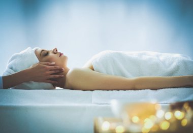 Masaj masasında uzanmış gözleri kapalı rahatlayan genç bir kadın. - Kadın. Spa salonu